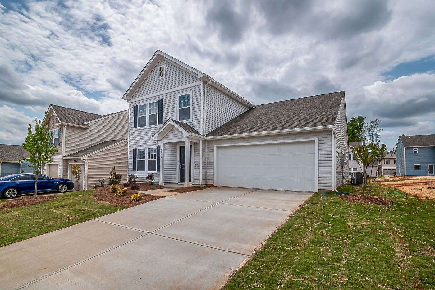Two-story Waco home with a double garage door under a broken Central Texas sky