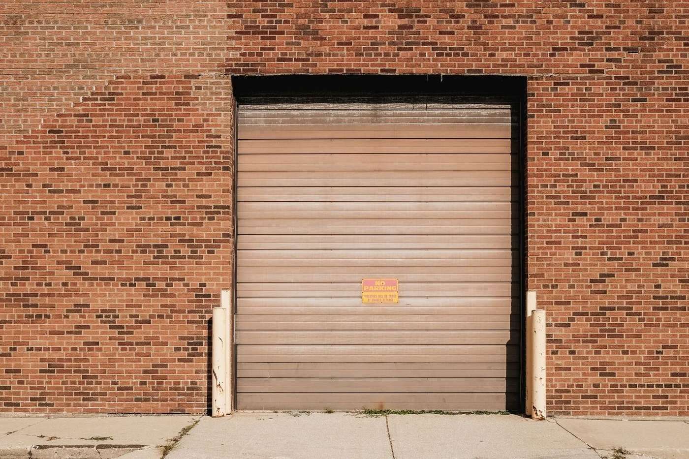 Steel roll-up overhead door set into the brick wall of a commercial warehouse unit