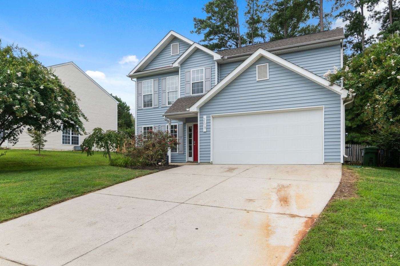 Wide white long-panel garage door on a gray-sided suburban house