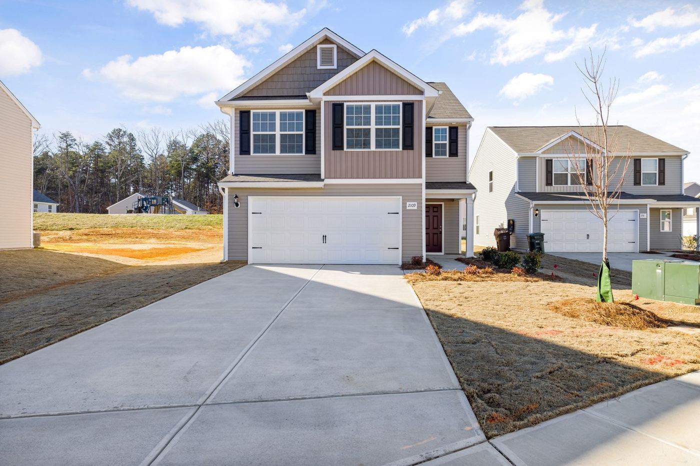 Newly installed white sectional garage door on a two-story home with a concrete driveway