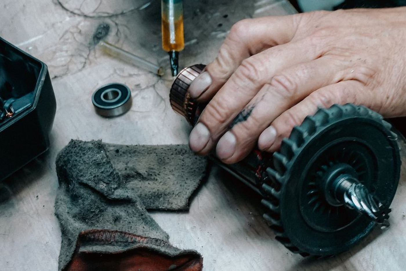 Technician hands rebuilding a toothed drive gear and motor assembly on a workbench