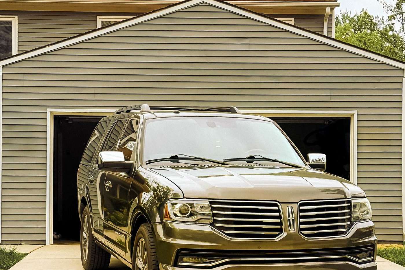 Open residential garage doorway with a vehicle inside and the safety sensor zone at floor level