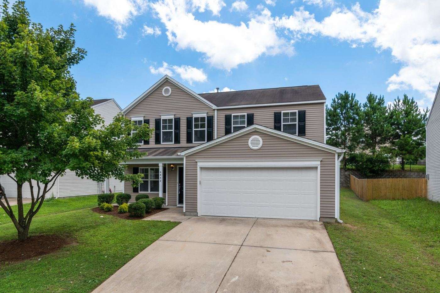 Two-story Hewitt home with a wide white double garage door and a long driveway