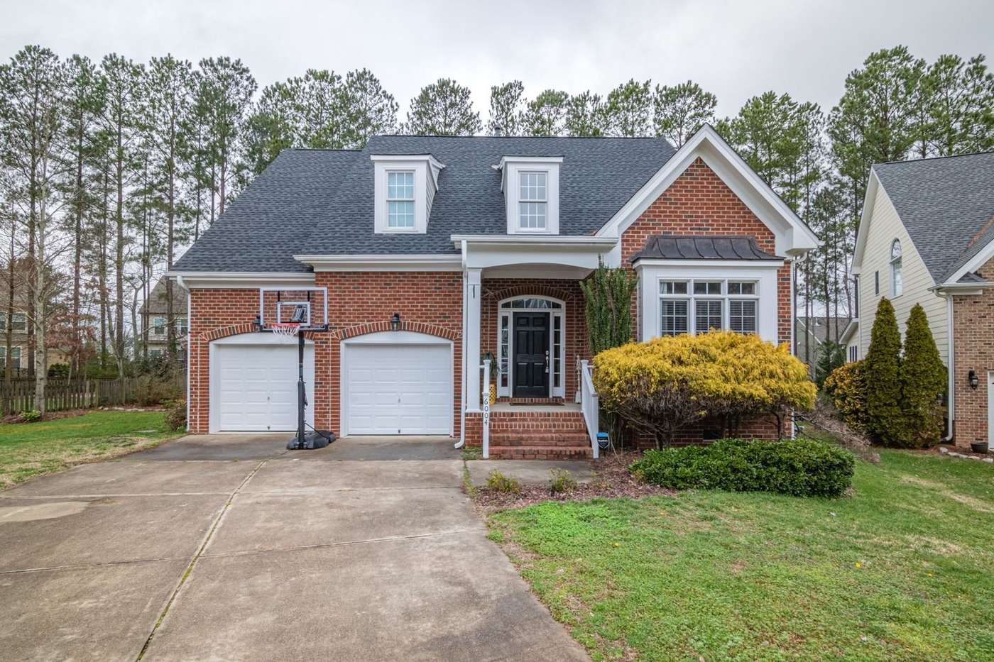 Brick two-story Woodway home with a pair of single garage doors facing a concrete driveway